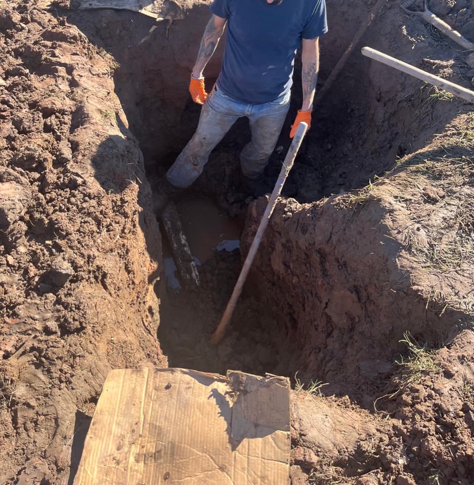 Wilson Plumbing technician working on piping inside an excavated trench
